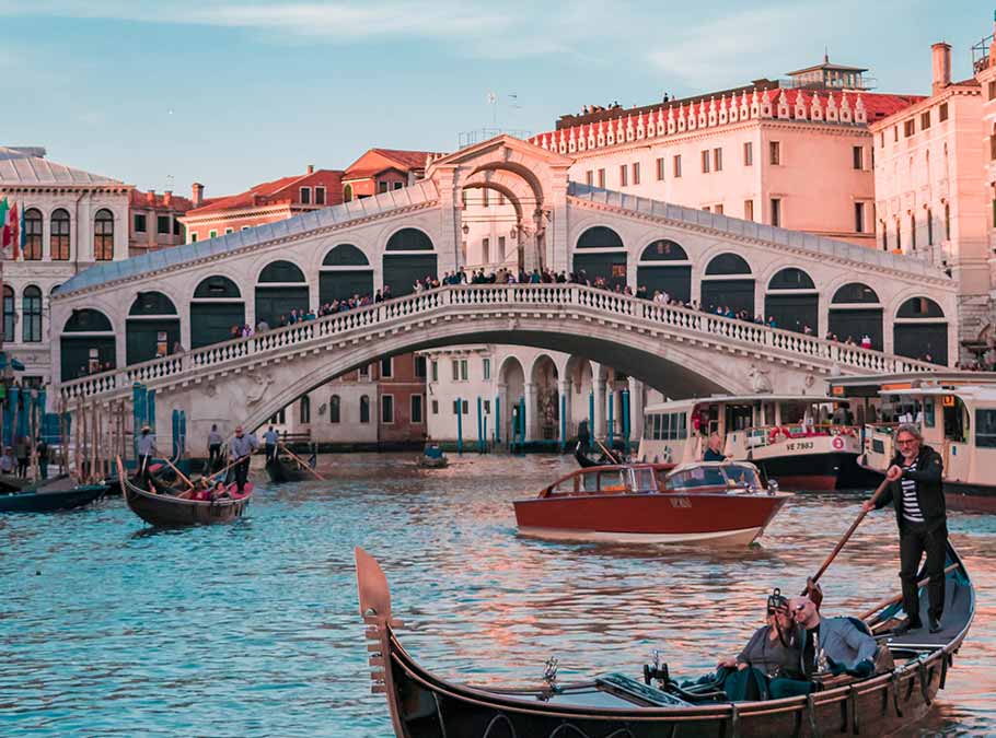 a couple take a selfie on a gondola tour with a Venetian boatman.