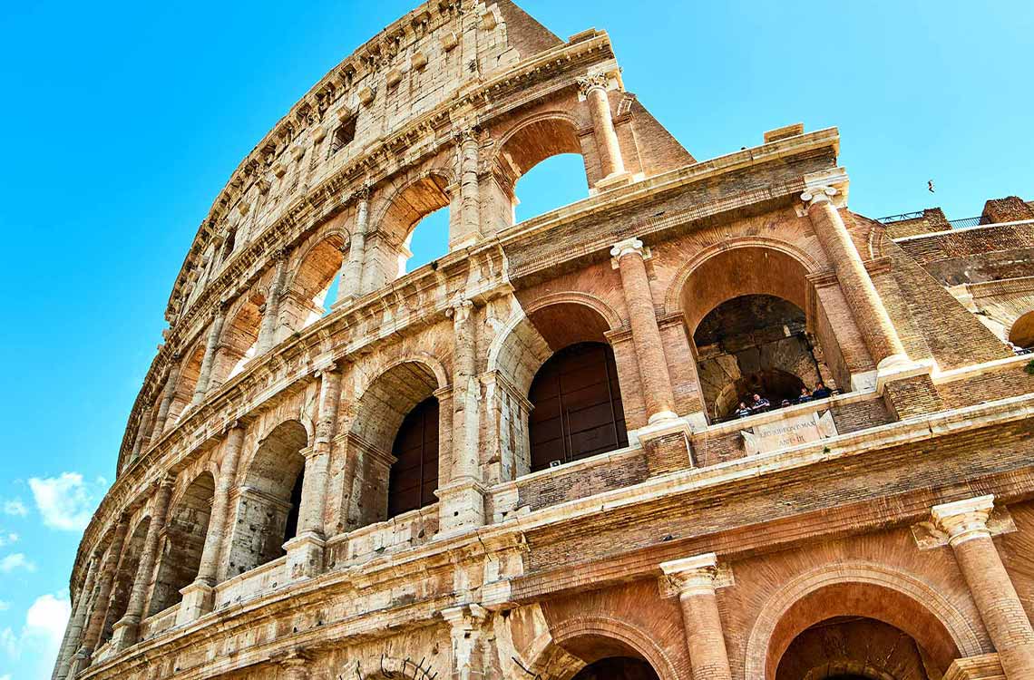 view of people on a private tour of the Colosseum visible through one of the structures arches