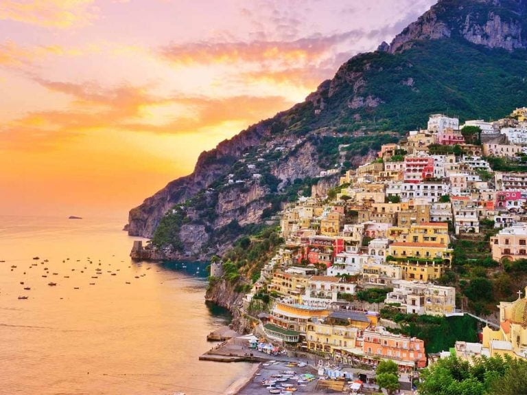 Colorful buildings built into the mountains overlooking the shore of the amalfi coast.