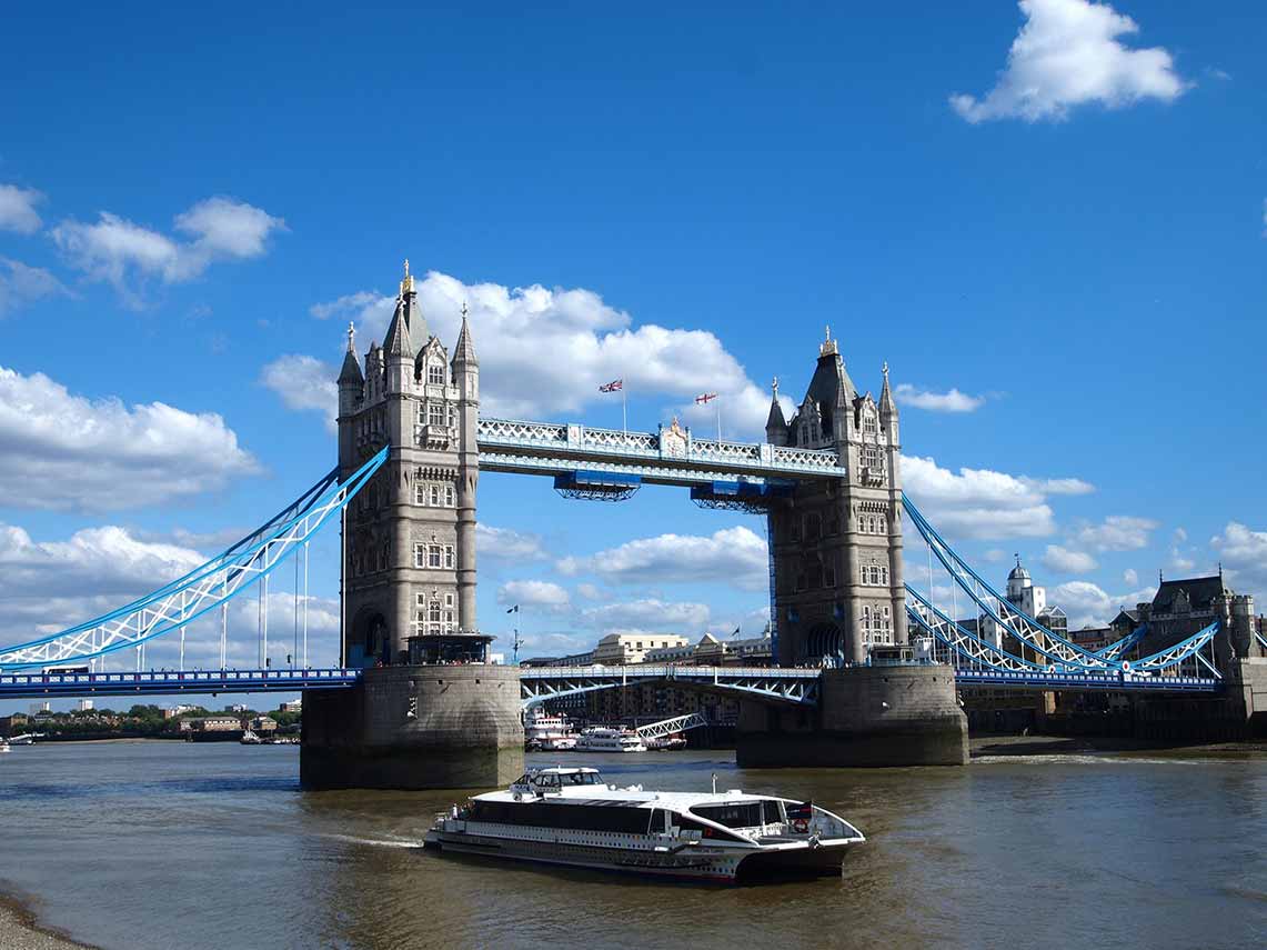 Enjoying a river cruise along the Thames with London Bridge in the background.