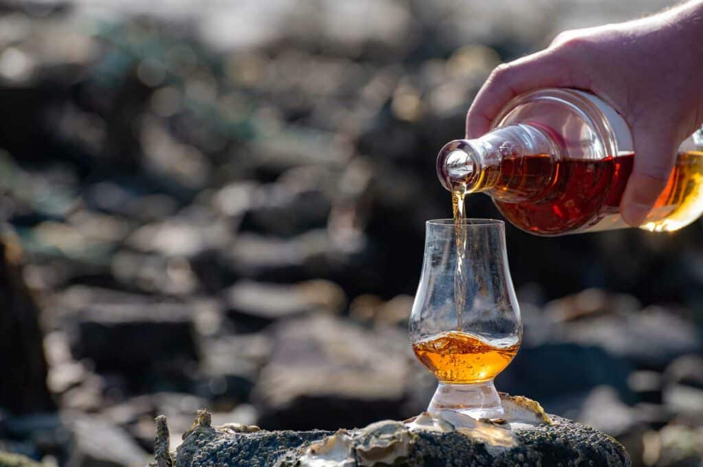 Pouring of Scotch whisky in tasting glass