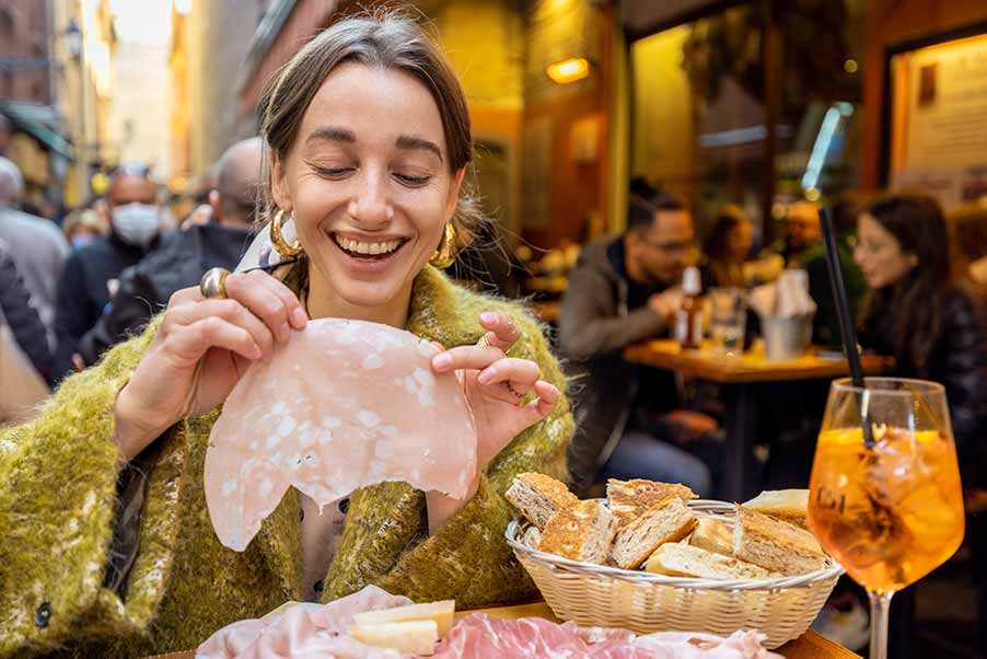 Italian food experience in Bologna Food Tour, Woman enjoying Italian ham and negroni.