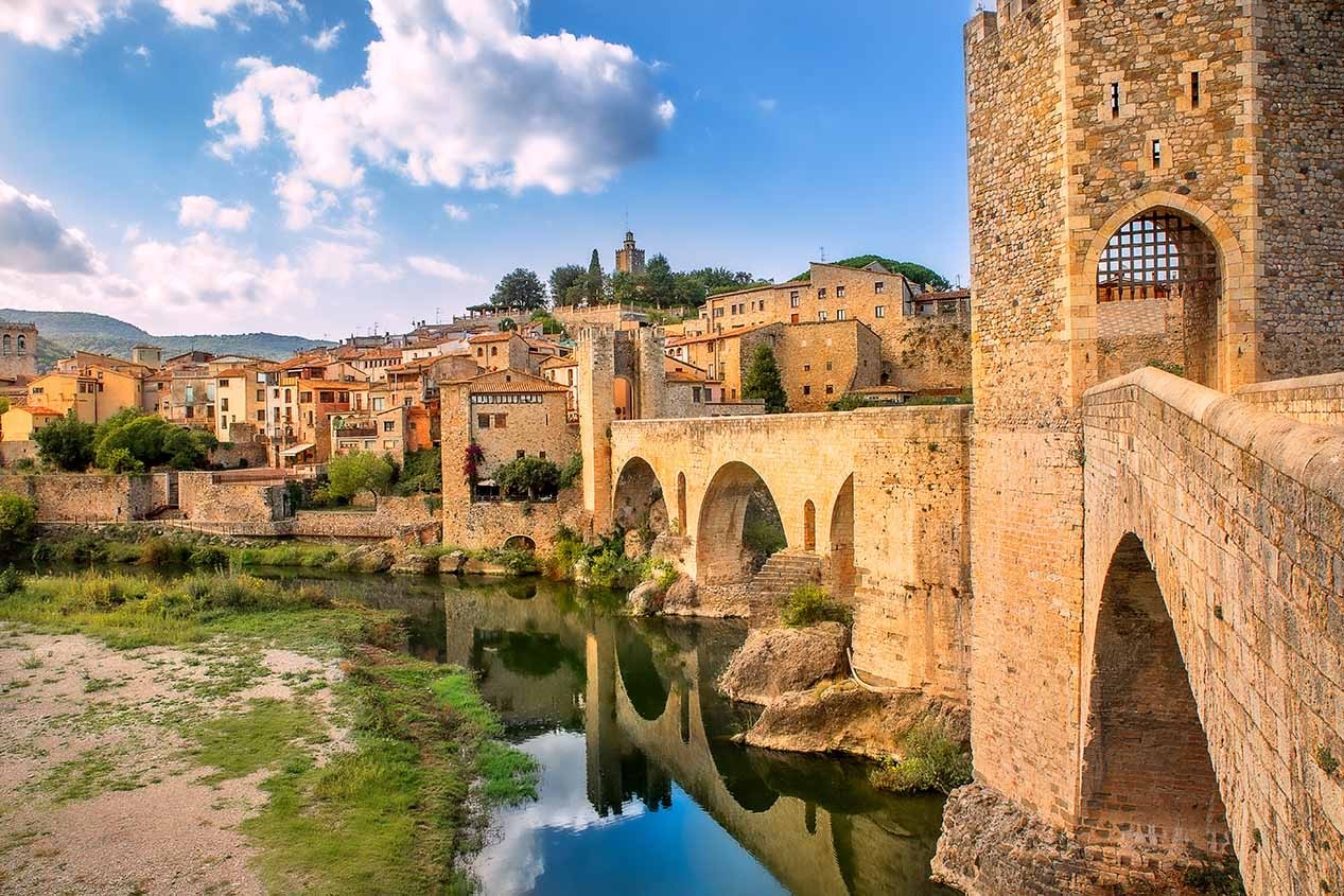 Girona, Catalonia, Spain. Famous landmark. Old medieval Romanesque bridge Besalu over the river Fluvia on a sunny summer day