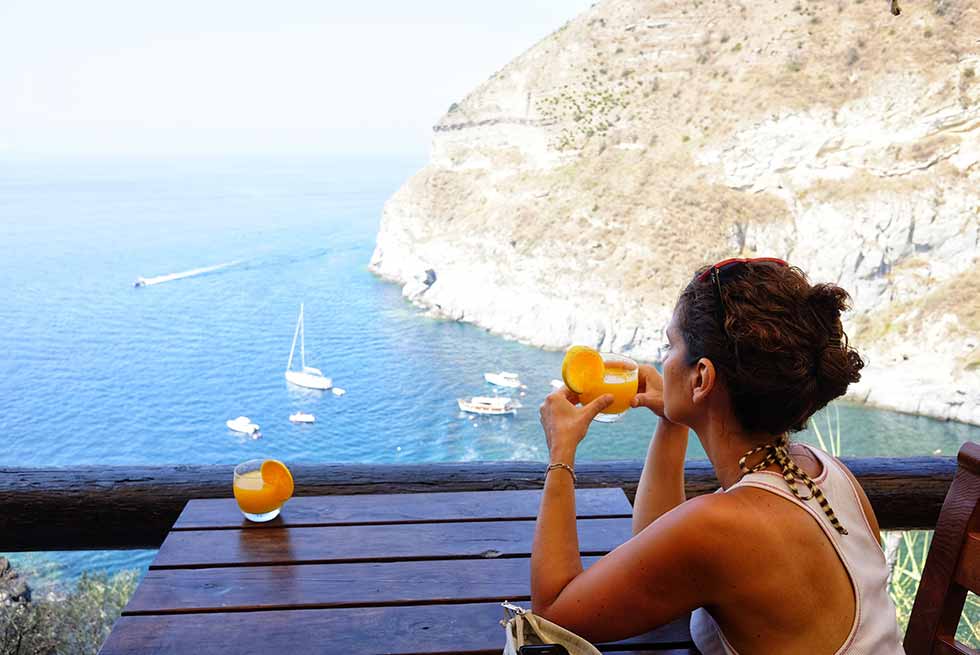 Woman enjoying lunch looking onto Bay of Sorgeto, Ischia