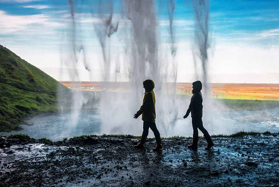 happy couple on tour standing underneath Seljalandsfoss Waterfall