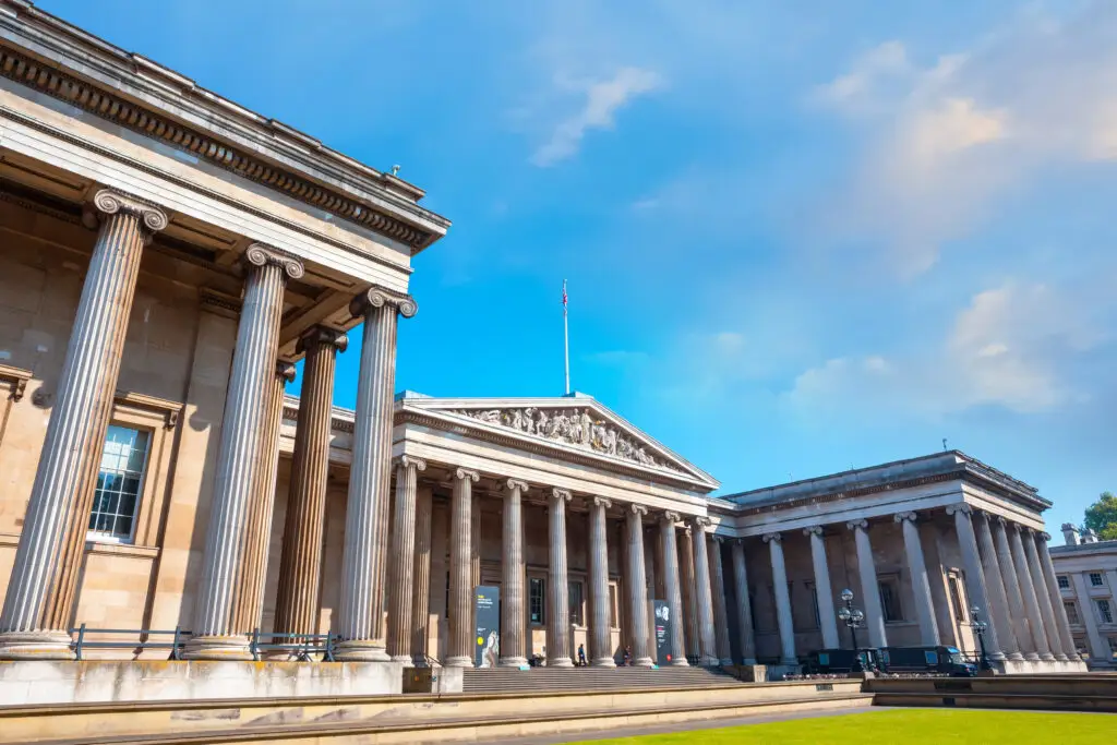 Bright sunny day at the British Museum in London, showcasing its majestic classical architecture with towering columns and sculptures.