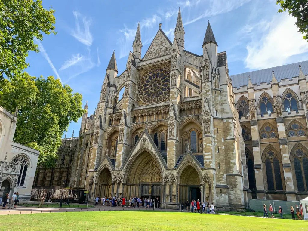 Visitors exploring the iconic Westminster Abbey with its intricate Gothic architecture on a sunny day in London, UK