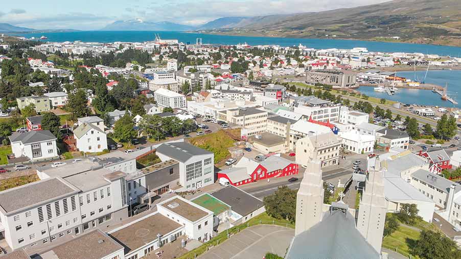 Aerial view of Akureyri, a charming town in Iceland, showcasing its colorful buildings, scenic landscape, and coastal setting.