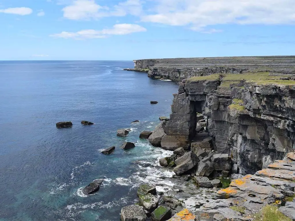 Scenic view of the rugged coastline and cliffs of the Aran Islands in Ireland, highlighting the natural beauty and clear blue waters of this popular tourist destination.