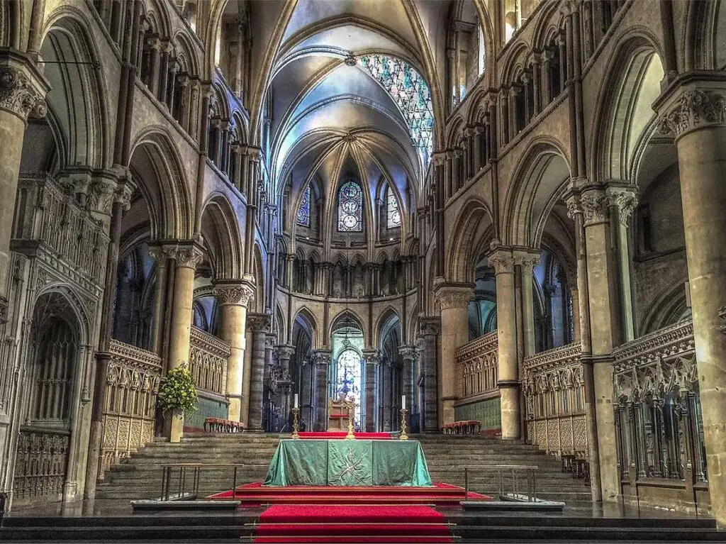 Interior view of Canterbury Cathedral in England showcasing the intricate gothic architecture, stained glass windows, and the altar.