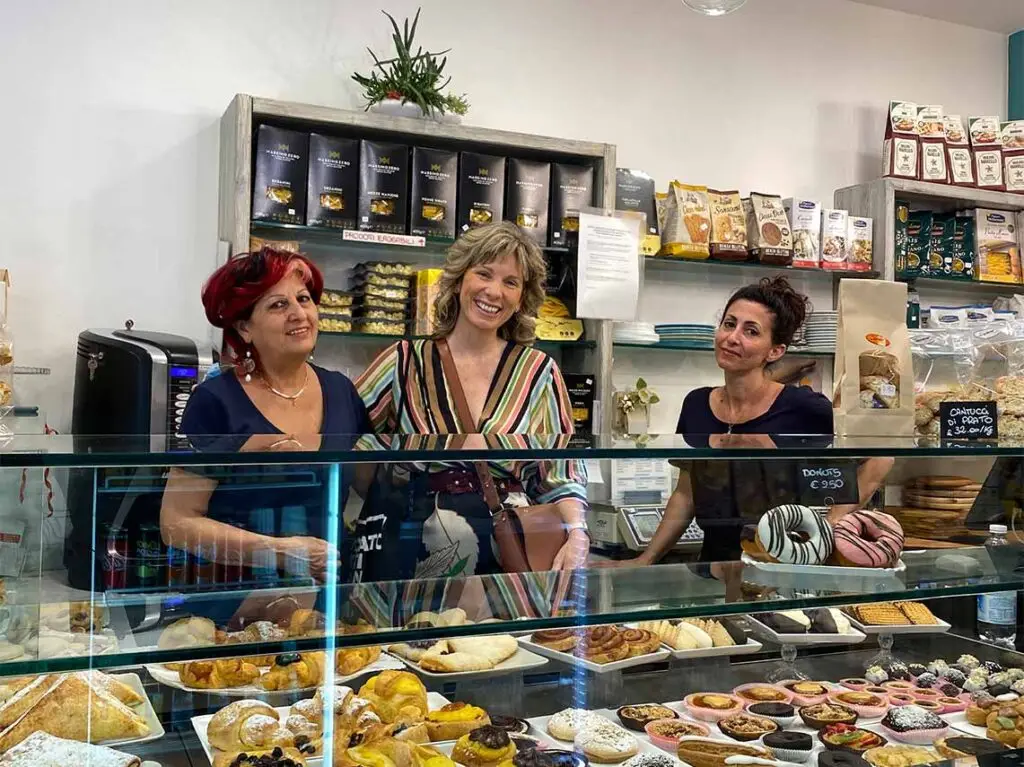 Tourists enjoying a Florence food tour at a local bakery showcasing an array of traditional Italian pastries and sweets.