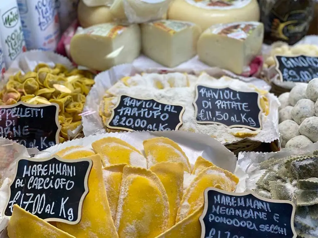 Variety of handmade Italian pastas and artisan cheeses displayed at a local market in Florence, perfect for a cooking class tour experience.