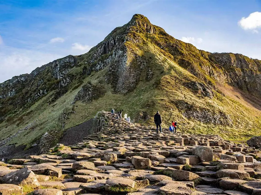 Tourists walking on the basalt columns of Giant's Causeway, a natural wonder and UNESCO World Heritage Site in Ireland