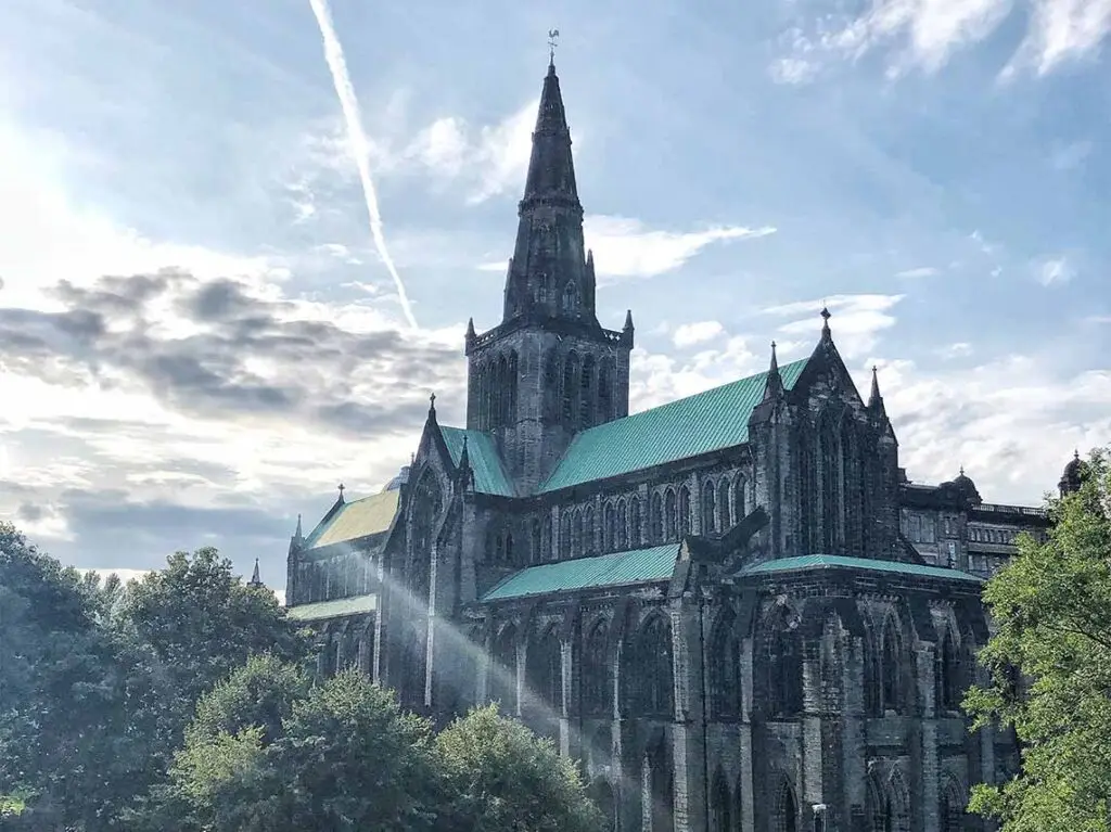 Majestic view of Glasgow Cathedral under a cloud-streaked sky in Scotland, a prime example of Gothic architecture and a popular tourist attraction.