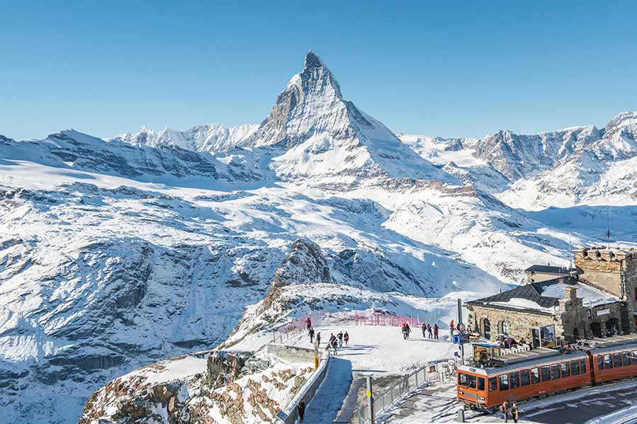 Gornergrat Bahn train at a station in Zermatt, Switzerland with picturesque view of Matterhorn and snowy landscape
