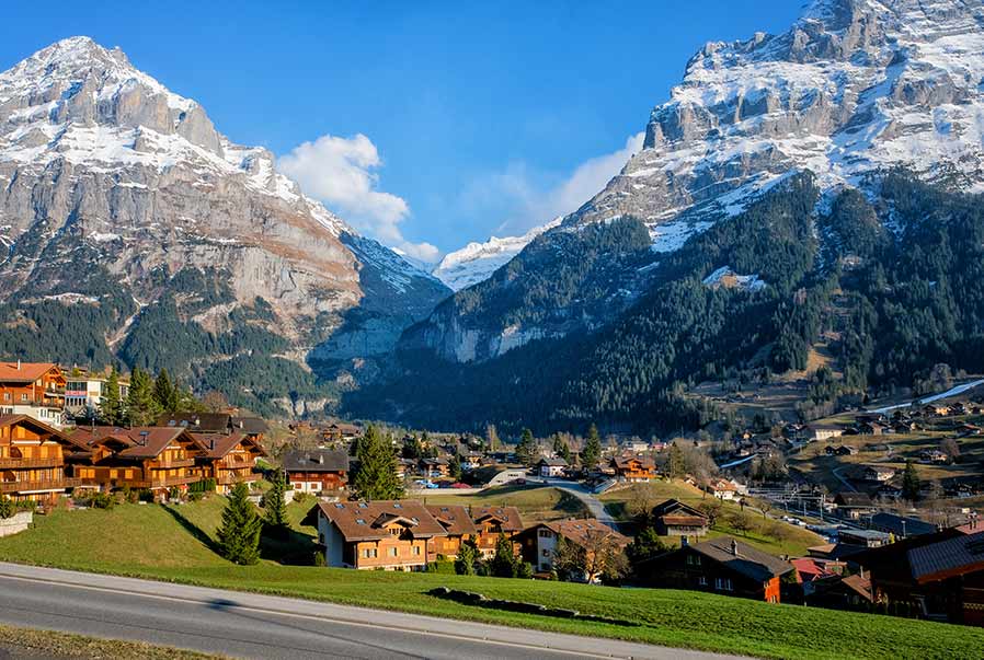 Scenic view of Grindelwald village with traditional Swiss chalets and majestic snow-capped mountains in Switzerland