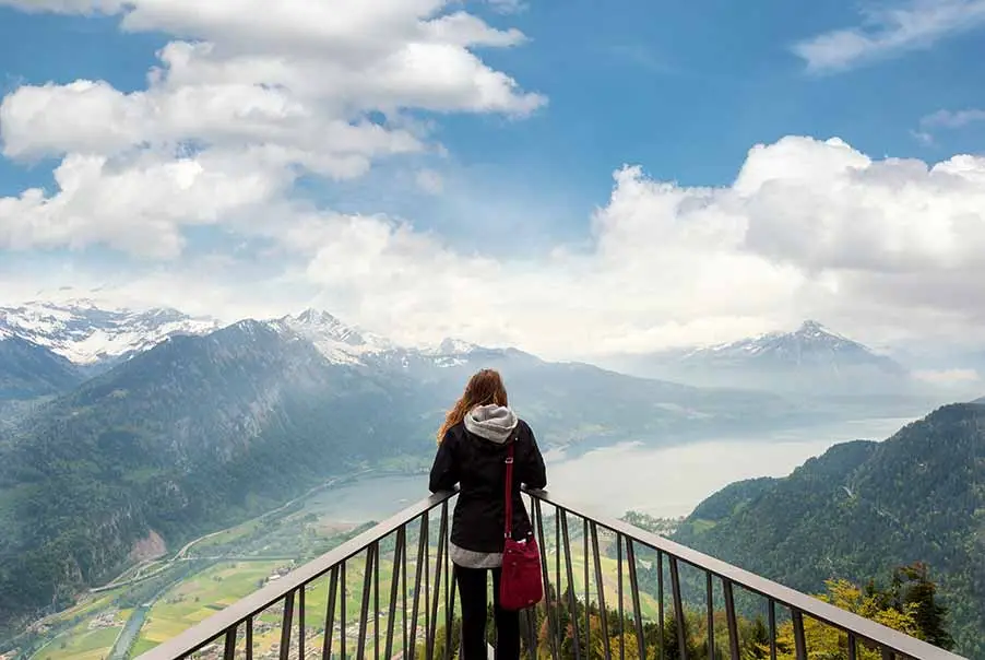 Tourist overlooking the scenic landscape of Interlaken, Switzerland, with majestic mountains and a serene lake in the background