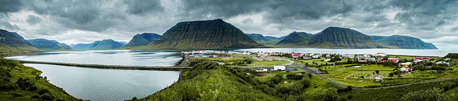 Panoramic view of Isafjordur town in the Westfjords of Iceland, showcasing its unique fjord landscape and vibrant houses under a moody sky.