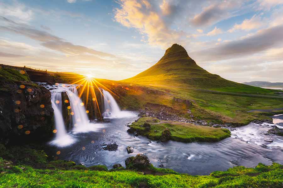 Sunset over Kirkjufellsfoss Waterfall and Kirkjufell Mountain in Iceland, picturesque tourism and travel destination.