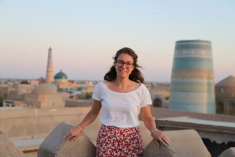 Smiling woman posing in front of ancient landmarks in Khiva, Uzbekistan during sunset