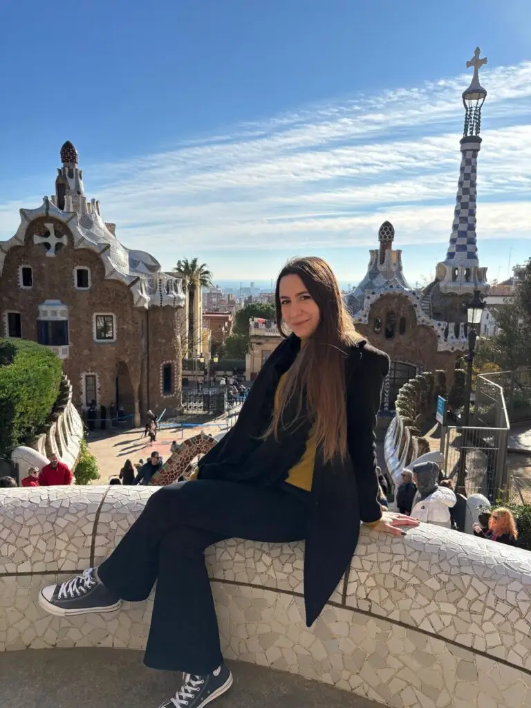 Woman enjoying a sunny day at Park Güell in Barcelona, showcasing the park's unique architecture and panoramic city views.