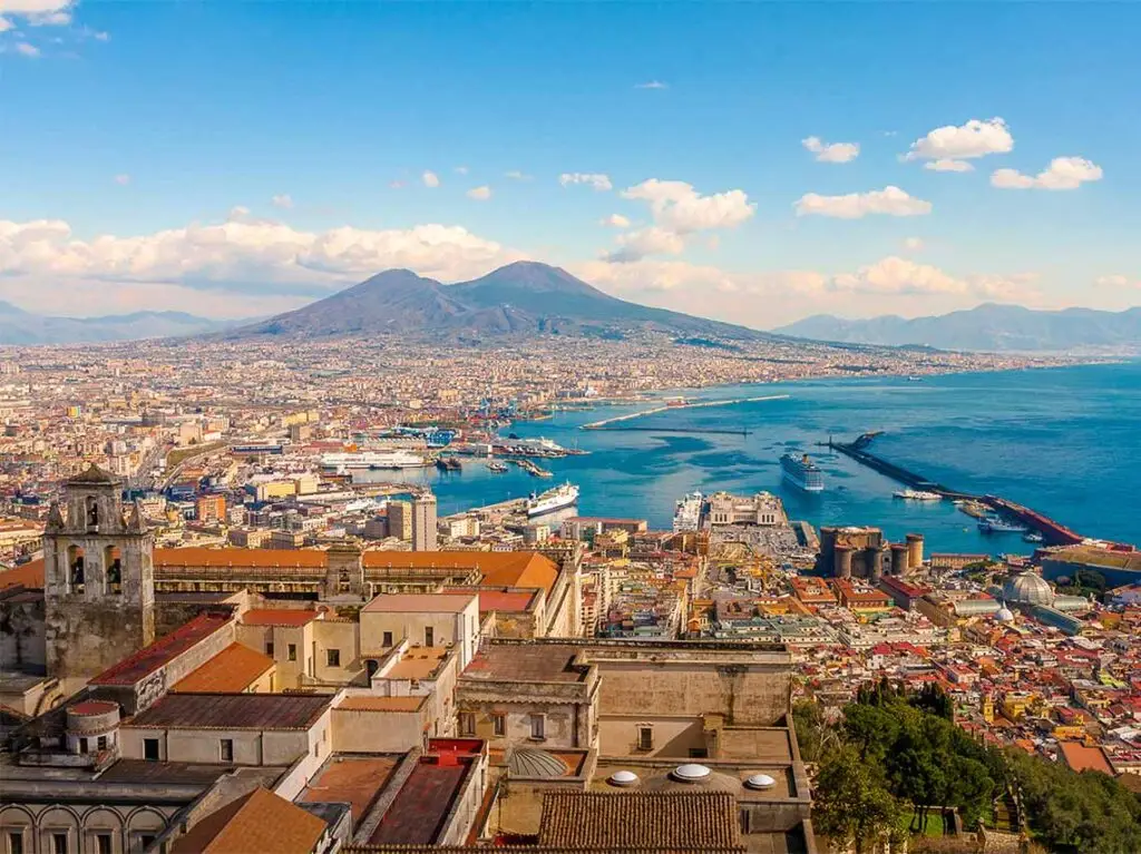 Panoramic view of Naples with Mount Vesuvius in the background, highlighting the vibrant cityscape and coastline on a sunny day, ideal for a walking tour.