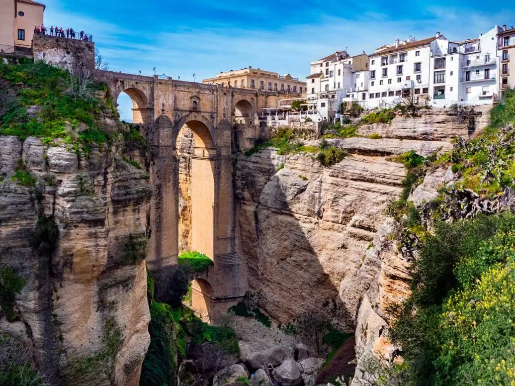 View of Puente Nuevo in Ronda, Andalucia, showing the bridge connecting two cliffs with tourists enjoying the panorama.