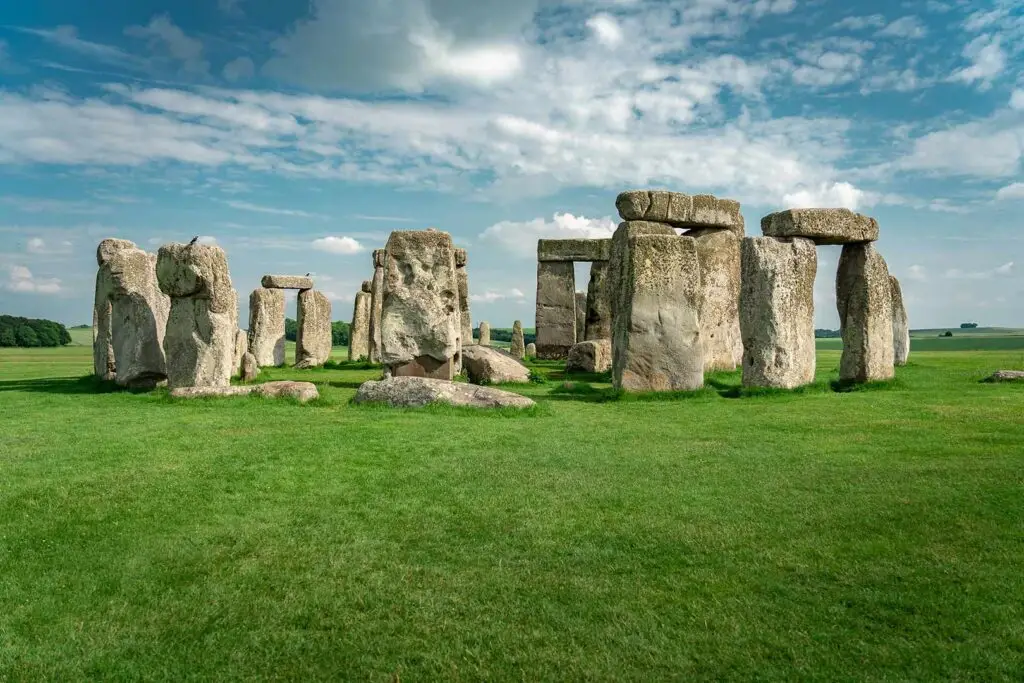Stonehenge, iconic prehistoric monument in Wiltshire, England, featuring large standing stones set against a scenic blue sky and green landscape.