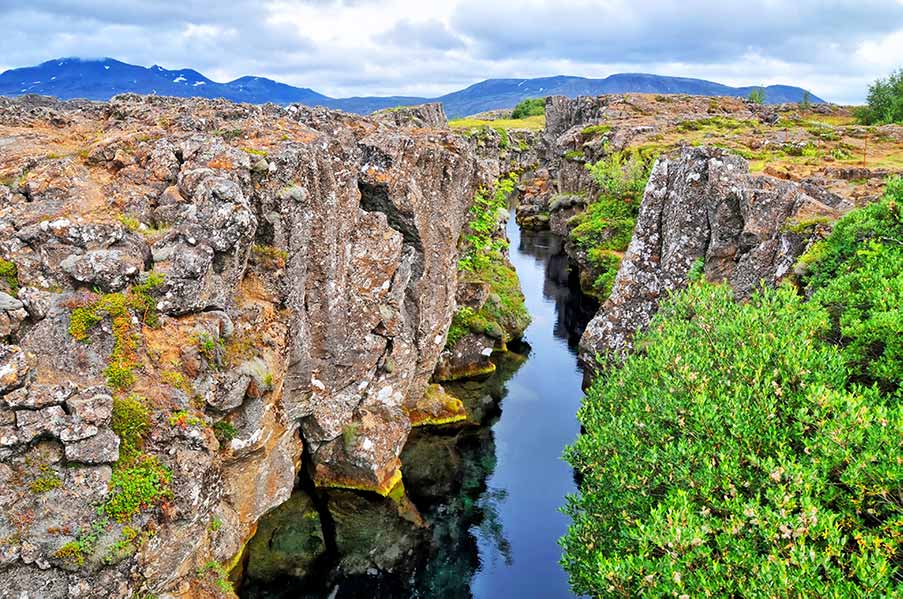 Scenic view of Thingvellir National Park in Iceland, showcasing dramatic rift valley landscapes with rugged cliffs and a serene river cutting through green vegetation