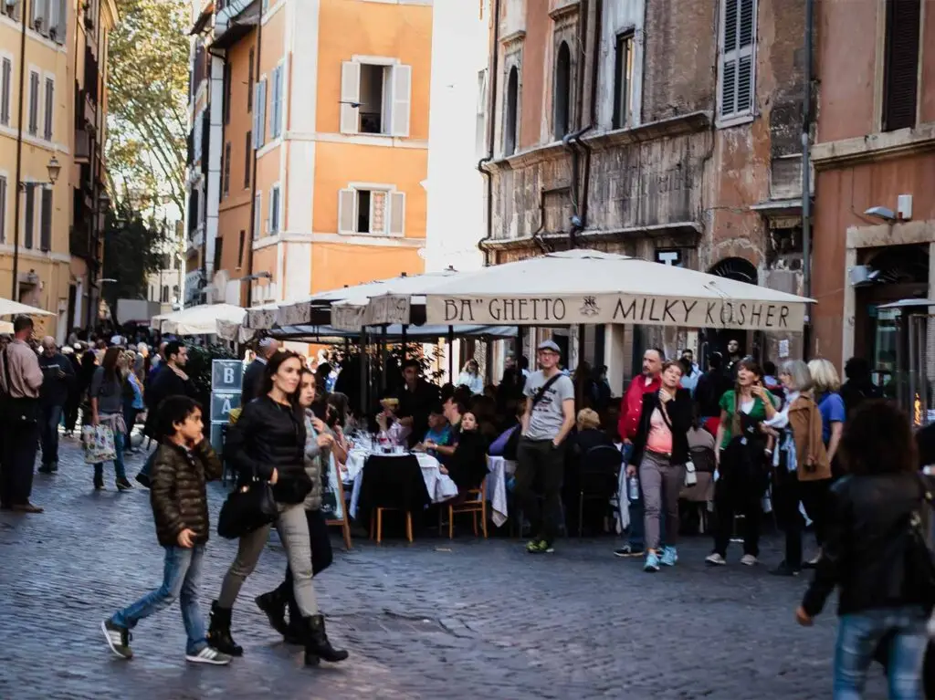 Tourists exploring the lively Trastevere neighborhood on a food tour in Rome, Italy, featuring outdoor dining and historic architecture.
