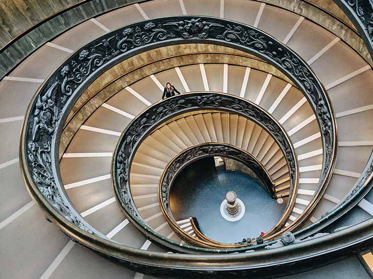 Tourist admiring the iconic double helix spiral staircase inside the Vatican Museums during a VIP Vatican tour.
