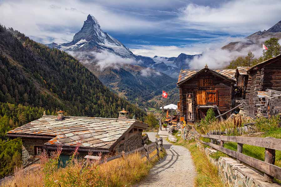 Scenic view of traditional Swiss chalets and the iconic Matterhorn mountain in Zermatt, Switzerland, showcasing the natural beauty and cultural architecture of the region.