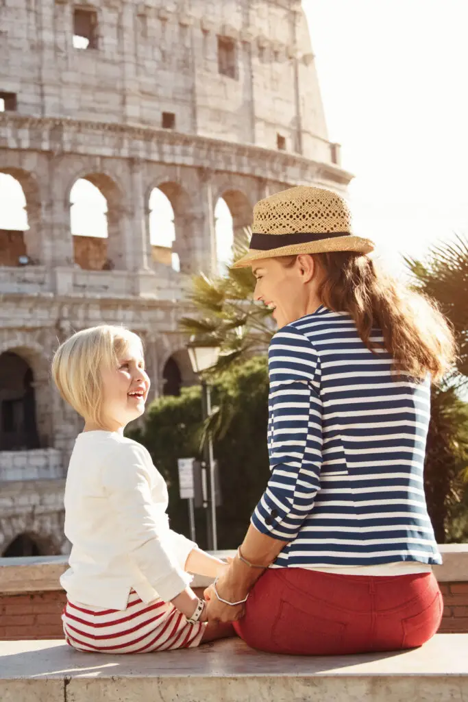 Happy mother and child tourists sharing a moment in front of the Colosseum in Rome, Italy, enjoying their vacation together.